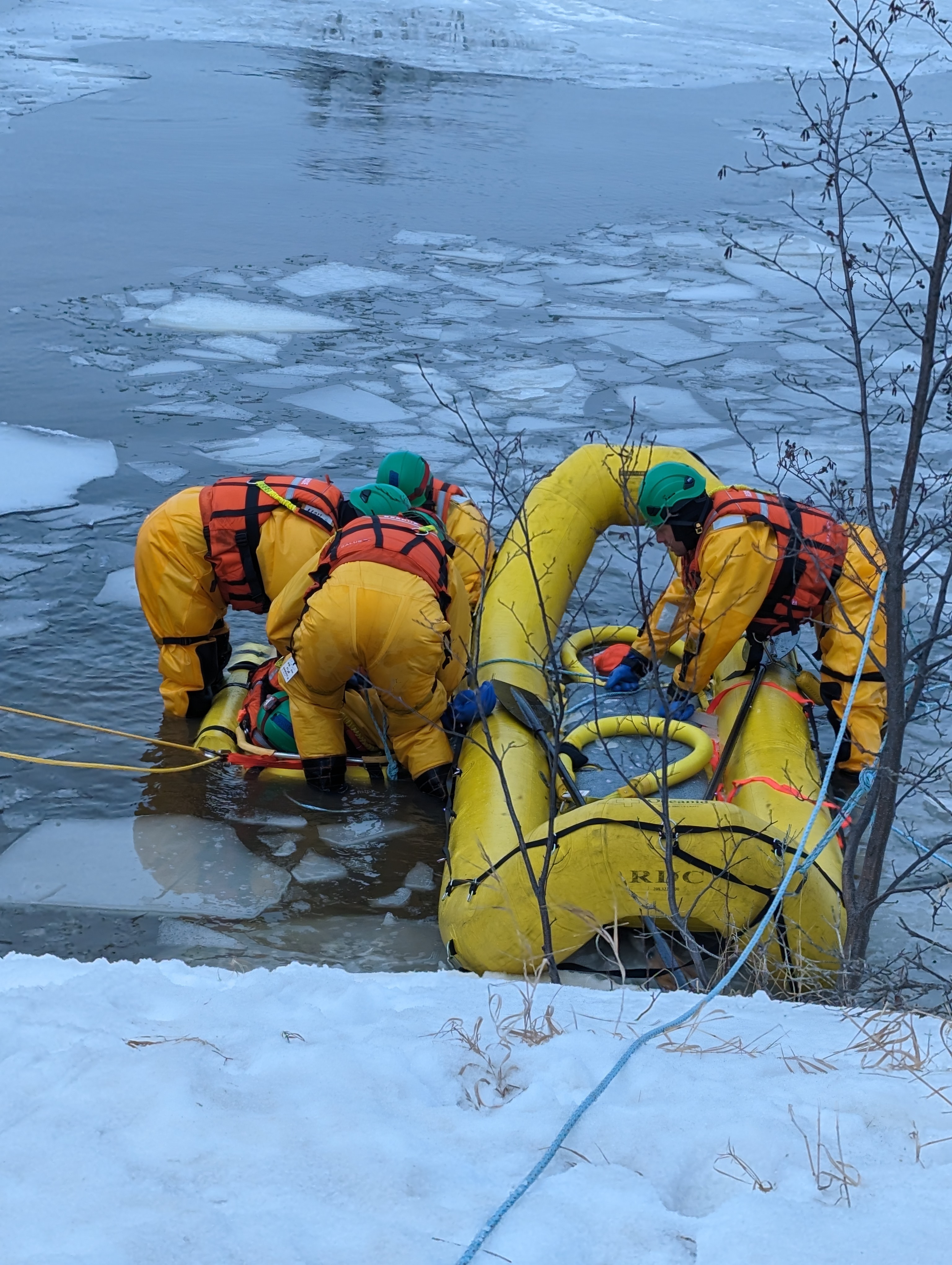 Firefighters training with ice water rescue equipment in the water