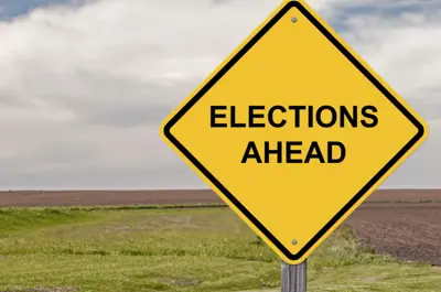 Road sign with field in the background saying "Elections Ahead"