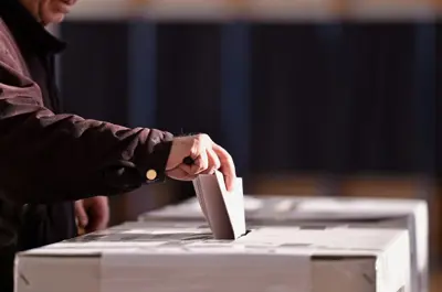 A ballot box with a ballot being submitted.